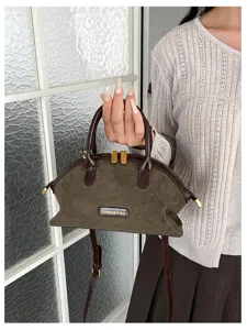 Vue détaillée du sac à main rétro en daim marron avec poignée en cuir foncé et ferrures.