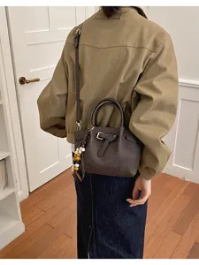 Sac seau texturé chic avec bandoulière et pendentif en perles pour le style quotidien.