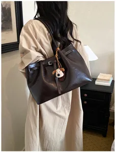 Detail view of the elegant brown tote bag with cute puppy pendant and retro belt strap design.
