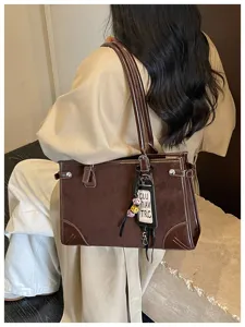 Detail shot of vintage brown commuter tote bag, casual shoulder bag with pendant decoration.