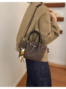 Vue détaillée du sac à bandoulière marron effet croco avec charm perles et boucle métal.