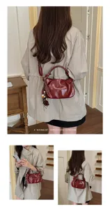 Détail de sac porté épaule plissé rouge vin, design rétro chic avec accessoires élégants.