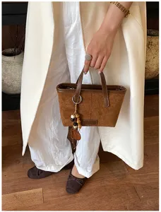 Retro suede bucket bag detailed view, elegant brown shoulder bag with decorative beaded charm.