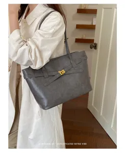 Minimalist grey tote bag featuring elegant strap buckle and metallic lock for daily commute.