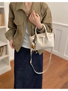 Sac à main bandoulière élégant avec motif crocodile et pendentif chic pour femme.