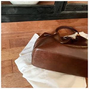Detail shot showing the texture and handle details of a vintage brown leather tote bag