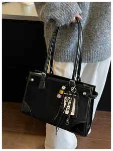 Black vintage tote shoulder bag detail showing premium texture, double handles, and chic charms.
