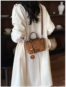 Retro suede shoulder bucket bag detail view showcasing minimalist vintage design and charm pendant.