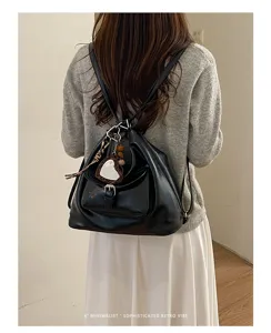 Detailansicht des stilvollen schwarzen Lederrucksacks mit herzigem Spiegel-Anhänger.