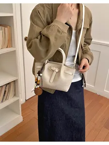 Vue détaillée du sac bandoulière en cuir crème avec motif croco et pendentif en perles.
