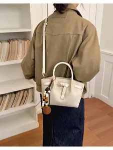 Sac à main blanc effet croco avec détail de boucle et charm de perles en bois.