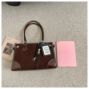 Detail view of the brown suede tote handbag featuring double handles and chic tag accessory.