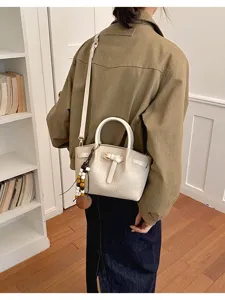 Sac à main blanc motif crocodile avec détail de nœud et pendentif perlé pour femme.