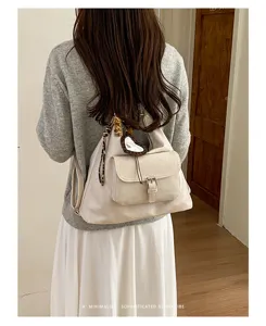 Detailansicht des lässigen Retro-Rucksacks in Beige mit Vordertasche und schickem Anhänger.