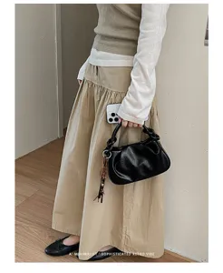 Gros plan détaillé du sac à main noir plissé, montrant son cuir souple et son charm chic.