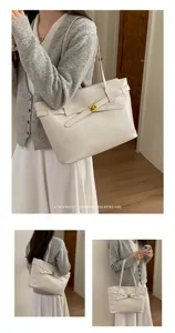 Detail view of a minimalist retro beige tote bag with belt detail and gold hardware.
