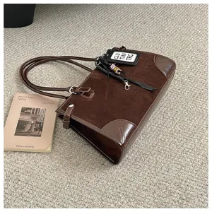 Brown suede vintage tote bag detail view showing texture, dual handles and decorative tag.