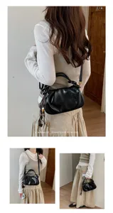 Vue détaillée du sac à main noir plissé, texture douce, poignée chic et design élégant.
