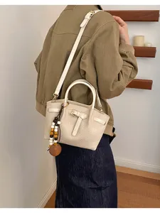 Sac à main chic en cuir motif crocodile blanc crème avec bandoulière et pendentif perles bois.