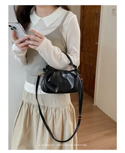 Vue rapprochée du sac porté épaule noir effet vernis plissé au design élégant.