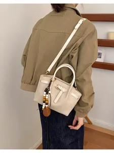 Détail du sac bandoulière blanc motif crocodile avec pendentif perles en bois