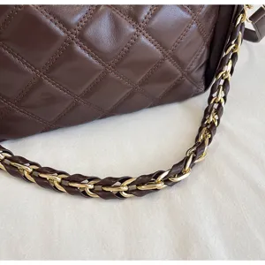 Nahaufnahme der braunen gesteppten Ledertasche mit goldener Kette, luxuriöse Texturansicht.