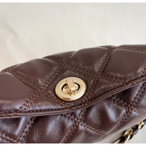Detailansicht der dunkelbraunen gesteppten Ledertasche mit elegantem goldfarbenem Metallverschluss.