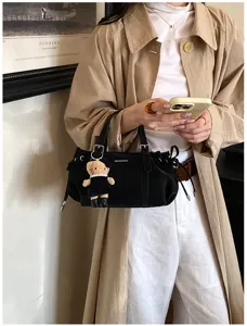 Gros plan du sac cabas noir à cordon avec joli pendentif en peluche, élégant et chic.