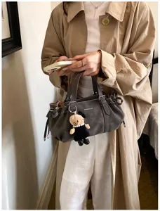 Vue détaillée du sac cabas gris à cordon avec joli pendentif pour un style tendance.