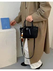 Vue détaillée du sac à main noir élégant avec boucle décorative et charm de perles chic.