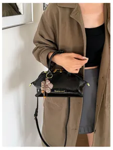 Vue détaillée du sac noir brillant, quincaillerie métallique chic et breloque.