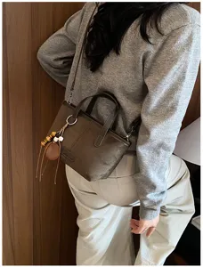 Close-up detail of retro brown suede crossbody bag styled with knit sweater and cute charm.