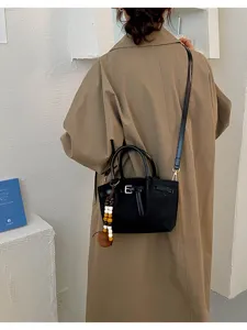 Élégant sac seau noir bandoulière avec breloque en perles de bois, sac à main mode et chic.