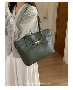 Detailed view of dark green retro tote bag with metal turnlock and shoulder strap on model