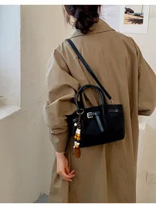 Sac à main noir élégant en cuir avec poignée supérieure et bandoulière pour un usage quotidien.