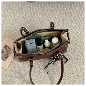Detailed view of large capacity brown retro tote bag interior storage space and daily items.