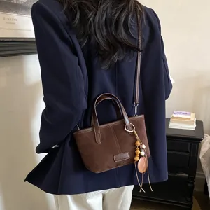 Retro suede crossbody bag for women, chic shoulder tote with bead pendant and vintage design.