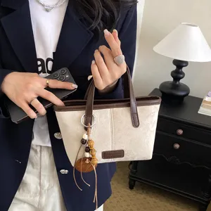 Retro suede canvas bucket bag women crossbody handbag with leather trim and pendant decor.
