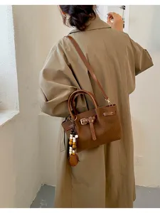Vue détaillée du sac à main marron en cuir effet croco avec boucle métal et pendentif perles.