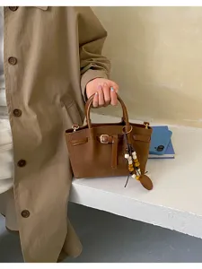 Élégant sac à main marron texturé avec sangle à boucle et charm perlé élégant pour femmes.