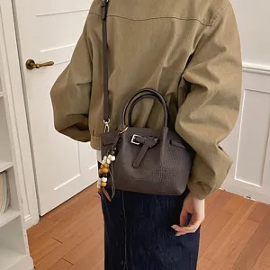 Élégant sac seau marron texturé avec poignée et bandoulière pour un usage quotidien.