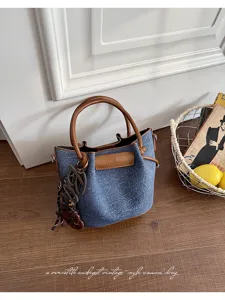 Vintage denim bucket bag for women, stylish brown leather trim and chic handle design.