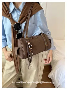 Braune Wildleder Boston Schultertasche Detailansicht mit Anhängern und Reißverschluss.