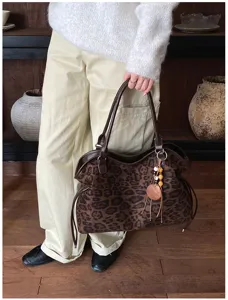 Detailed view of retro leopard print suede tote bag with cute charm pendant in scene.