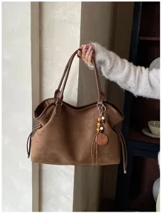 Brown vintage faux suede tote bag detail, featuring shoulder straps and wooden bead charm.