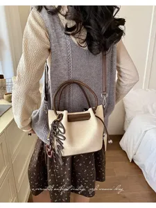 Chic vintage style women bucket bag with pleated design, brown handles and charm.