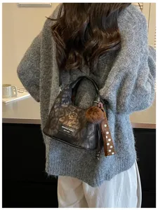Koreanischer Vintage Leopardenmuster Handtaschen Detail-Shot mit Puschel und Schleife.