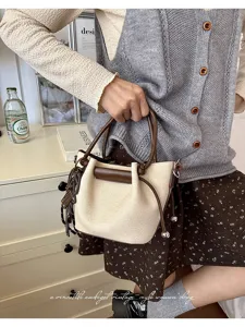 Detail shot of stylish women handbag featuring beige pleated design and brown handles for autumn.