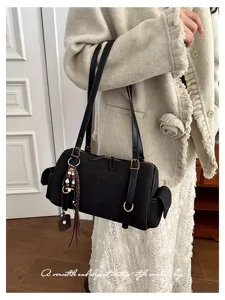 Detailaufnahme einer schwarzen Vintage-Umhängetasche mit Seitentaschen und schickem Anhänger.