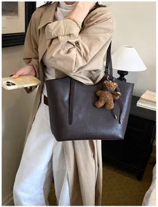 Vue détaillée du sac cabas en cuir marron foncé avec charmant porte-clés et design élégant.